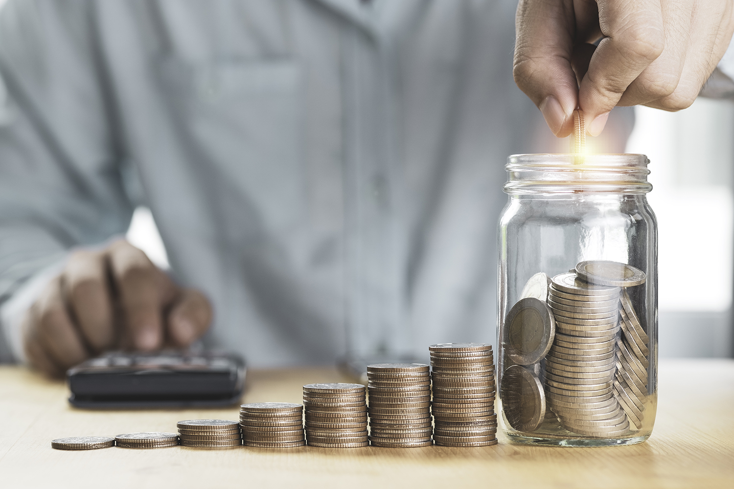 save-money-investment-concept-businessman-putting-coin-saving-jar-with-coins-stacked-using-calculator